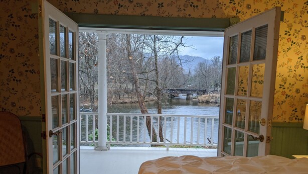 A room with a bed, a chair, and a view of a river and bridge. - Southern charm Riverside (Bryson City)