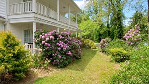 A two-story house with a covered porch and a garden with flowering shrubs. - Southern charm Riverside (Bryson City)