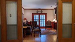 A room with wooden flooring, a large window with a view, a chair, a table, and a lamp. - Southern charm Riverside (Bryson City)