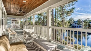 A covered porch with a view of a lake, furnished with a sofa, chairs, and a table. - Exclusive Pet-Friendly Watersound West Beach Retreat with Electric Cart, Bikes, Pool & Beach Access (Santa Rosa Beach)