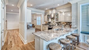 A spacious kitchen with a large island, pendant lighting, and a view to the living area. - Exclusive Pet-Friendly Watersound West Beach Retreat with Electric Cart, Bikes, Pool & Beach Access (Santa Rosa Beach)