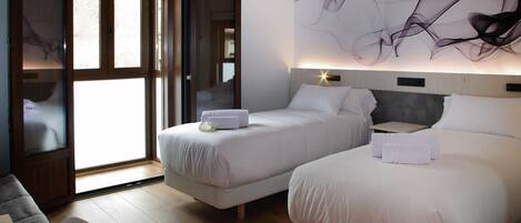 A hotel room with two beds, a large window, and a modern abstract painting on the wall.
