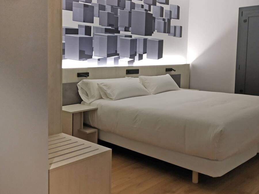Un dormitorio moderno con cama, mesitas de noche y una lámpara de pared.