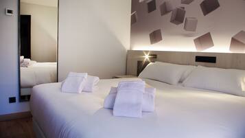 A hotel room with a large bed, a bedside table, a mirror, and a wall with geometric light fixtures.