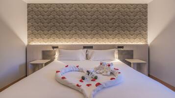 Una habitación de hotel con una cama grande, un cabecero de diseño geométrico y dos mesitas de noche con lámparas.