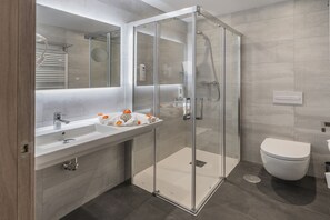 Une salle de bain moderne avec une douche à parois de verre, un lavabo blanc et des toilettes.