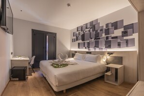 Une chambre d’hôtel moderne avec un grand lit, un bureau et un luminaire fixé au mur.