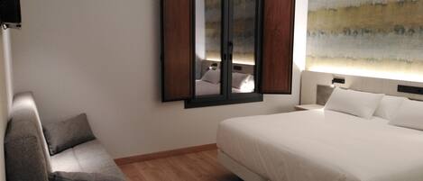 A hotel room with a bed, a desk, a chair, and a large window with a view.