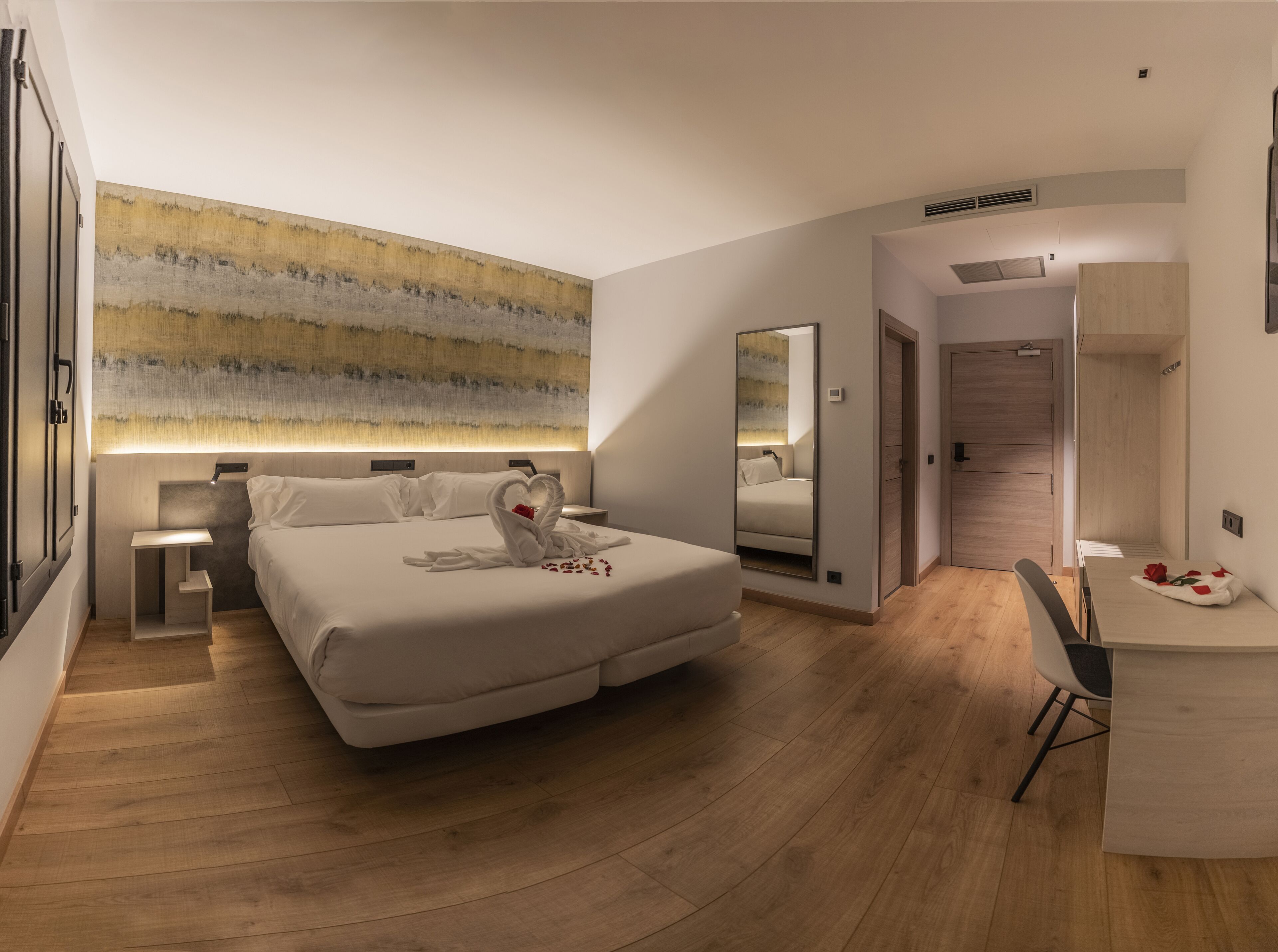 A modern hotel room with a large bed, a desk, and a shower area.