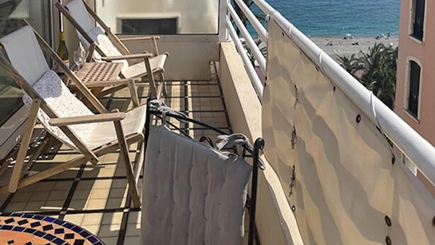 A balcony with two lounge chairs, a small table, and a red awning. The balcony overlooks a beach and the sea. - Perfect location at Promenades des Anglais, with balcony and a sea view. (Nice)