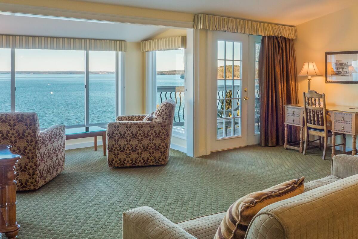 Habitación de hotel con vista al mar, un balcón con una silla, un escritorio y una lámpara.