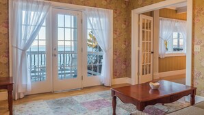 Una habitación con una mesa de madera, un tapete estampado y vista al mar a través de un ventanal.