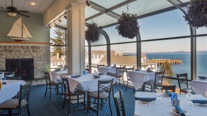 Un restaurante con mesas dispuestas para comer, una chimenea y vistas al mar.