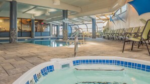 Un área de piscina interior con jacuzzi, sillones de descanso y un bar junto a la piscina.