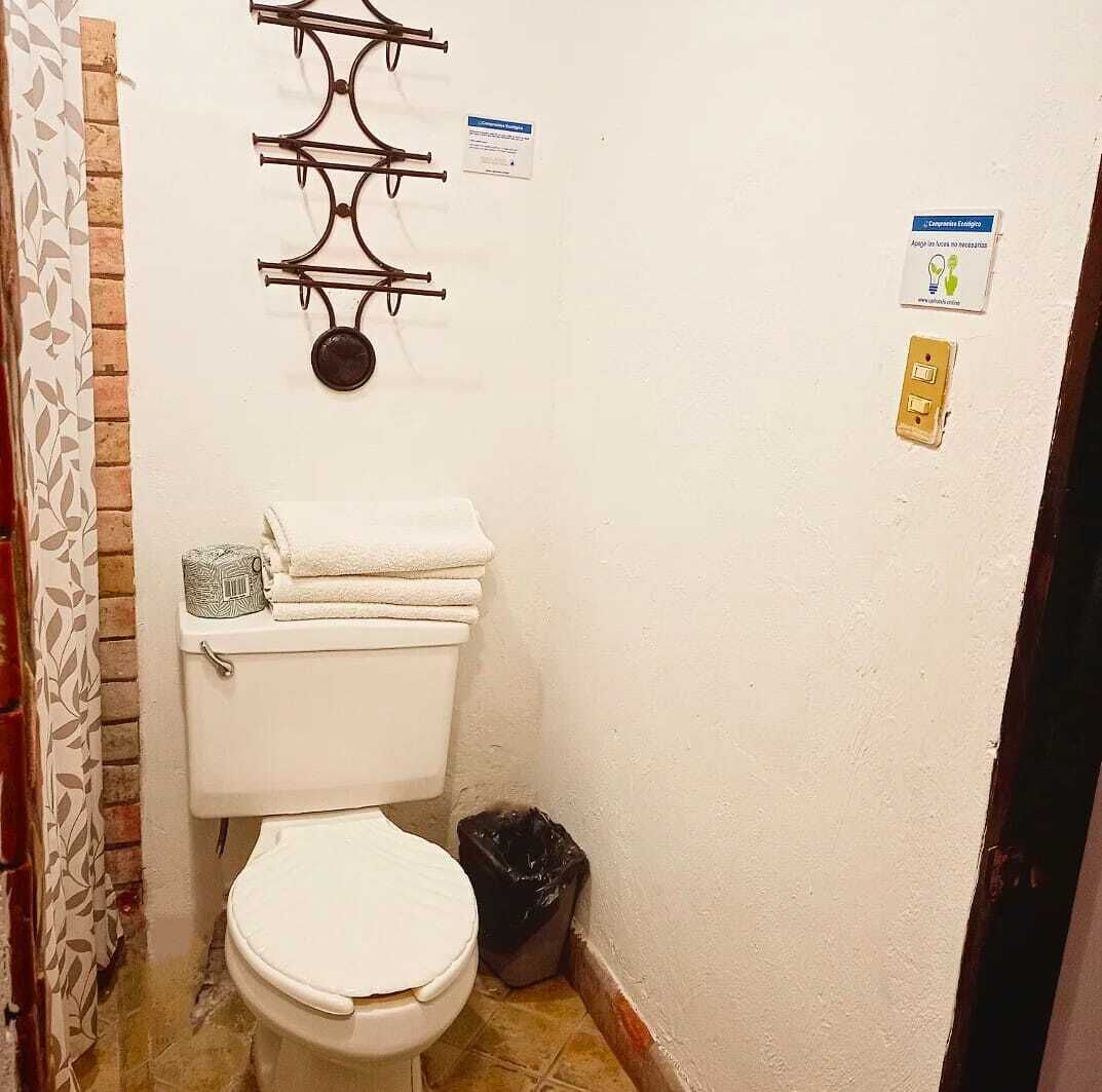Un baño pequeño con un inodoro, un bote de basura y un perchero para toallas.