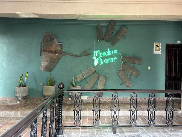 A wall with a neon sign reading "Monclova Mi amor" and a decorative metal piece with a broken chain. - Hotel Olimpia Centro Histórico (Monclova)