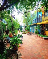 Un patio con plantas en macetas, mobiliario exterior e iluminación colgante.