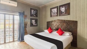 Habitación de hotel con una cama grande, cabecero de madera y vistas a través de un ventanal.