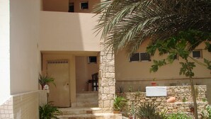 A courtyard with a stone pathway leading to a door, surrounded by potted plants and a stone wall. - costa do sol (Boa Vista)