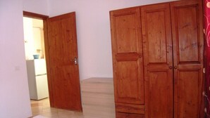A bedroom with a bed, wooden wardrobe, and a small dresser. - costa do sol (Boa Vista)