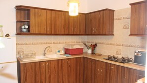 A kitchen with wooden cabinets, a sink, a dish rack, a red storage bin, and a gas stove. - Private villa for families, with private pool and beautifully furnished (Pereybere)