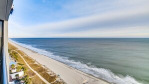 Une vue sur la côte depuis un balcon donnant sur une plage de sable et l’océan.