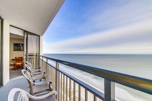A balcony with a view of the ocean, a dining area with chairs, and a table. - Ocean Front Condos at Patricia Grand (Myrtle Beach)