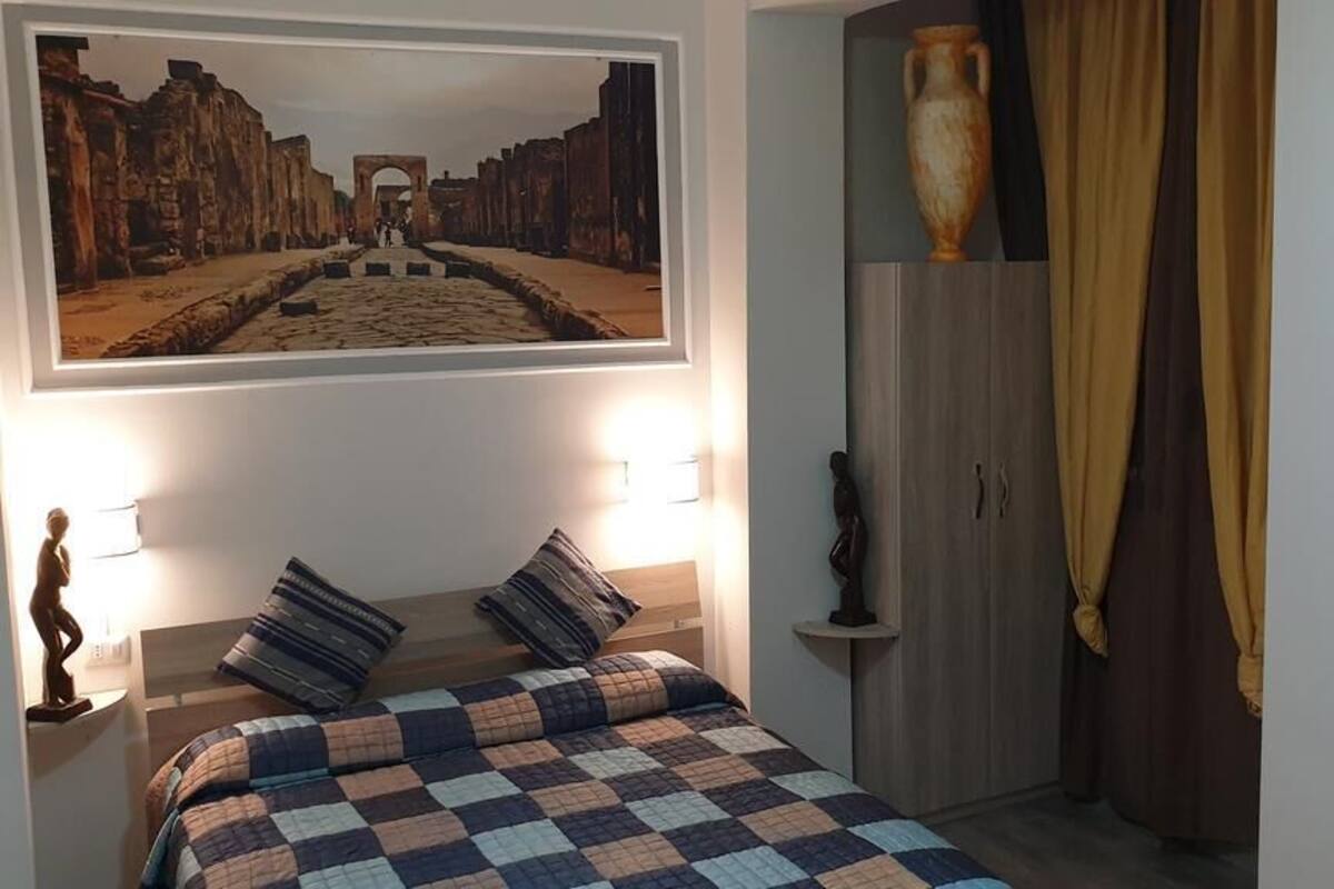 Een slaapkamer met een bed, een lijst met een foto aan de muur, een nachtkastje en een kledingkast.