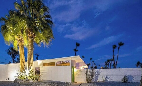 A modern house with a flat roof, large windows, and a well-lit entrance.