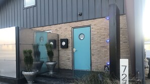 A building entrance with a blue door, potted plants, and a number sign '724' indicating the property number. - The Hangar Lofts Hotel (Columbia)