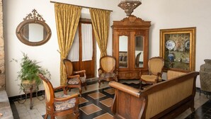 A traditional living room with a sofa, chairs, a wooden cabinet, and a mirror.
