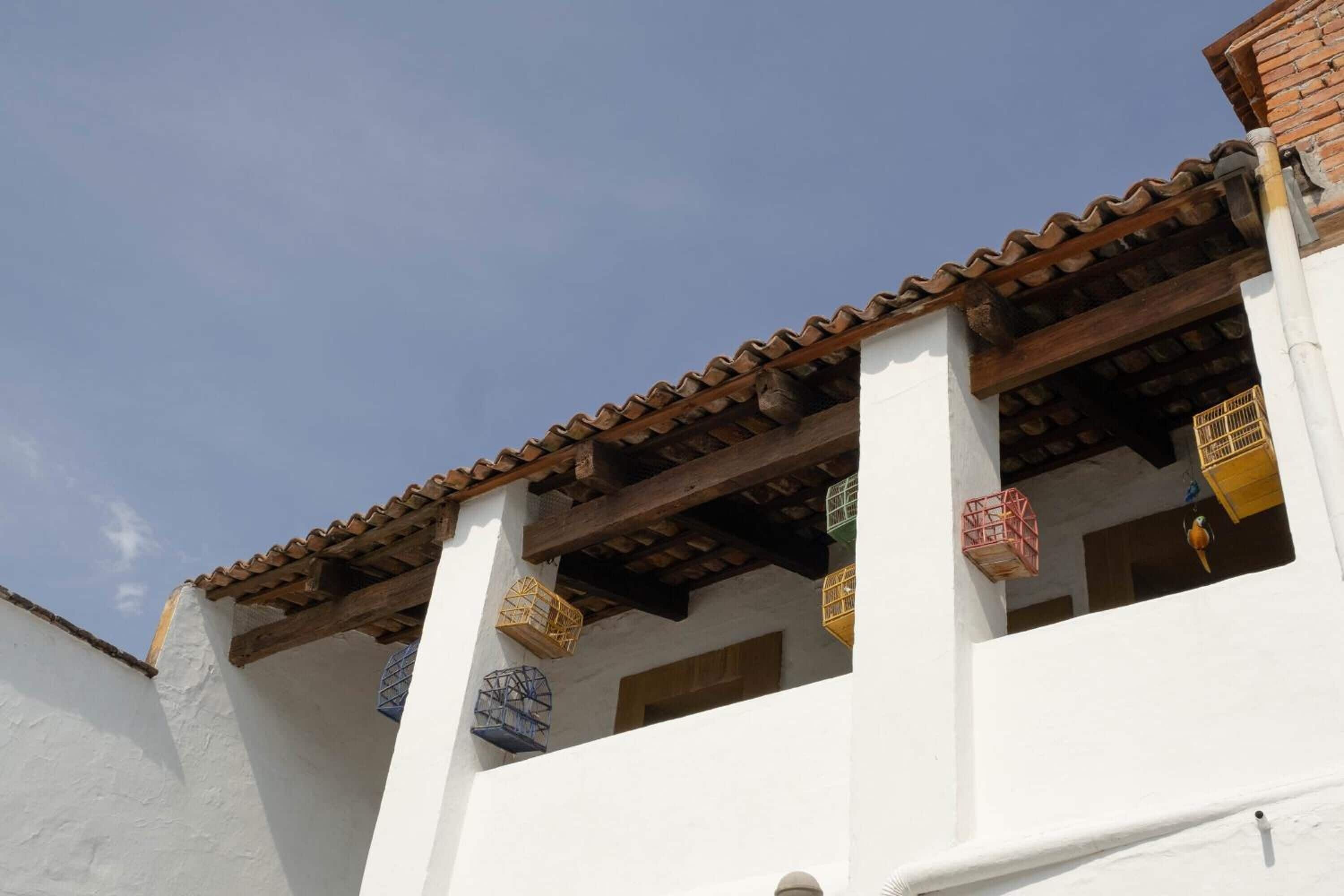 A building with white walls and a tiled roof. There are colorful hanging lanterns and a wooden beam structure.