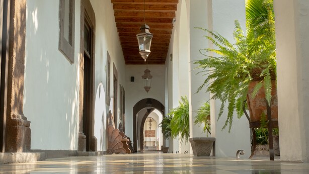 A corridor with tiled flooring, wooden beams, and hanging lanterns.