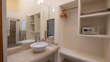 Un baño moderno con un espejo grande, dos lavamanos, un perchero y una repisa con una toalla y un microondas.