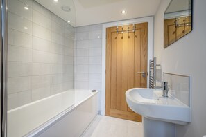 Un baño moderno con bañera, lavamanos y puerta de madera.