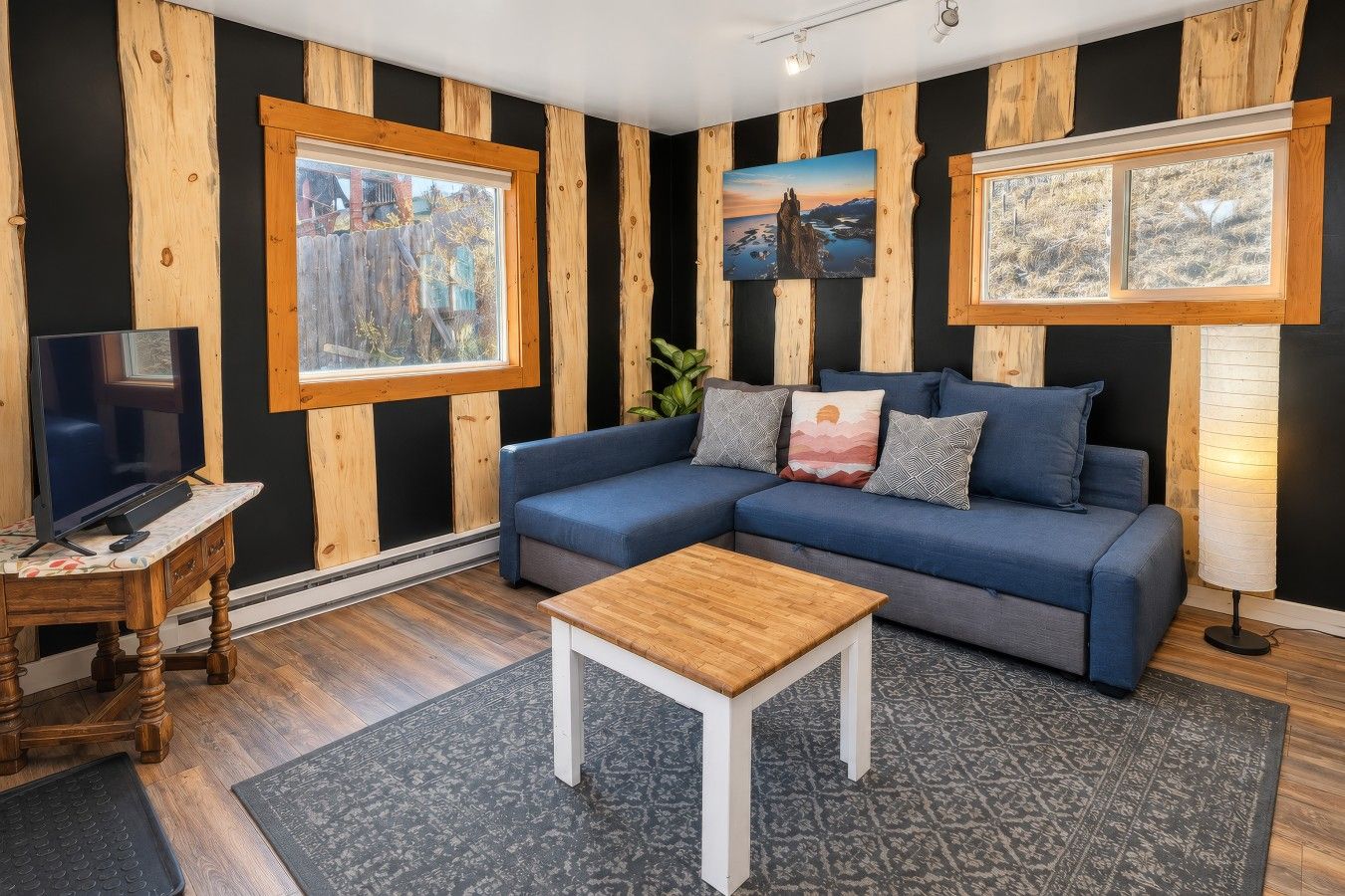 A living room with a sectional sofa, a coffee table, a TV on a wooden stand, and framed pictures on the walls.
