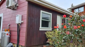 Una casa con fachada roja, una ventana y un rosal al frente.