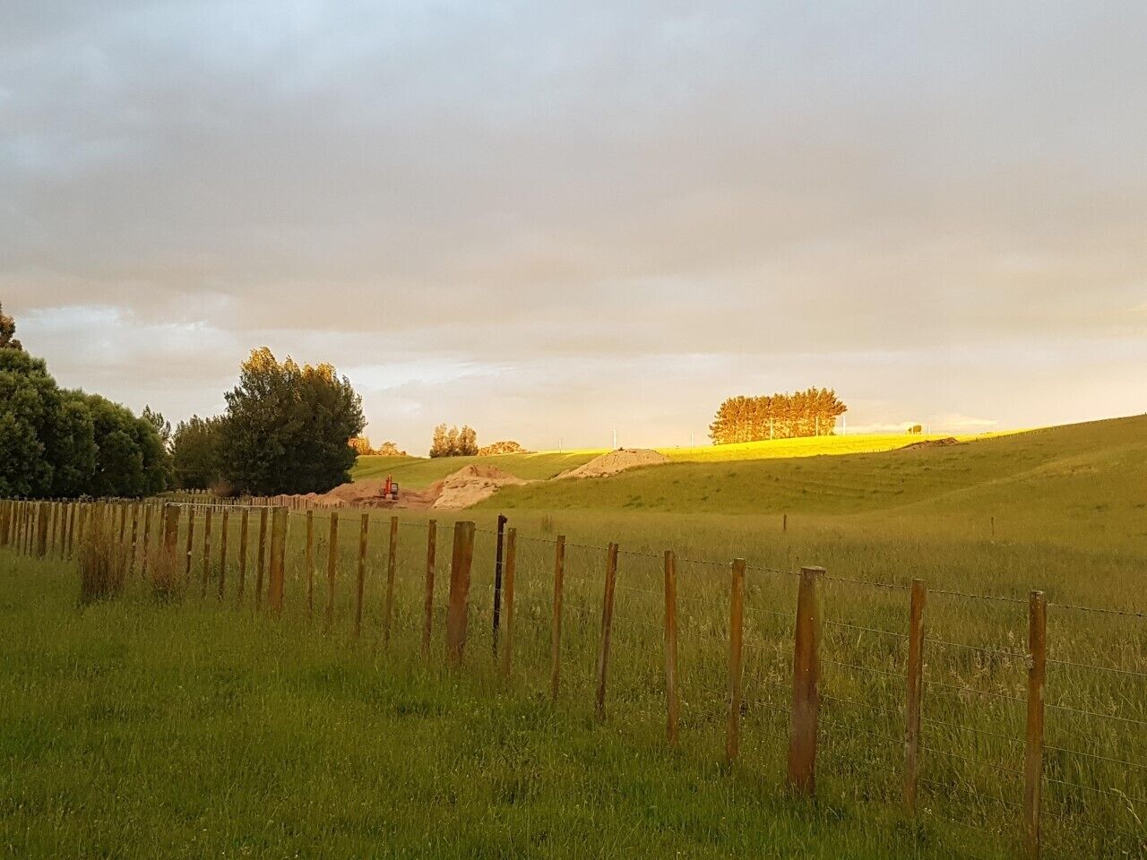 A grassy field with a wooden fence and a dirt path.