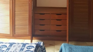 Una stanza con un armadio in legno, un letto con copriletto decorato e un pavimento piastrellato.
