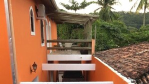 Una piscina con bordo in legno e una sedia, circondata da pareti arancioni e vegetazione.