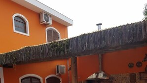 Area piscina con barbecue, tetto di paglia e parete piastrellata con decorazioni.