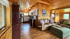 Een chalet van binnen met een keuken, eethoek en woonkamer.