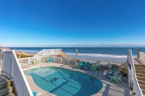 A pool area with a view of the beach and ocean.