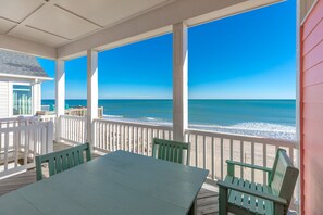 A covered outdoor area with a view of the ocean, featuring a table and chairs.