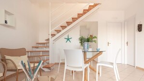 A modern living room with a staircase, white furniture, and a decorative starfish on the wall. - Blu Mediterraneo House - 1 (Ispica)