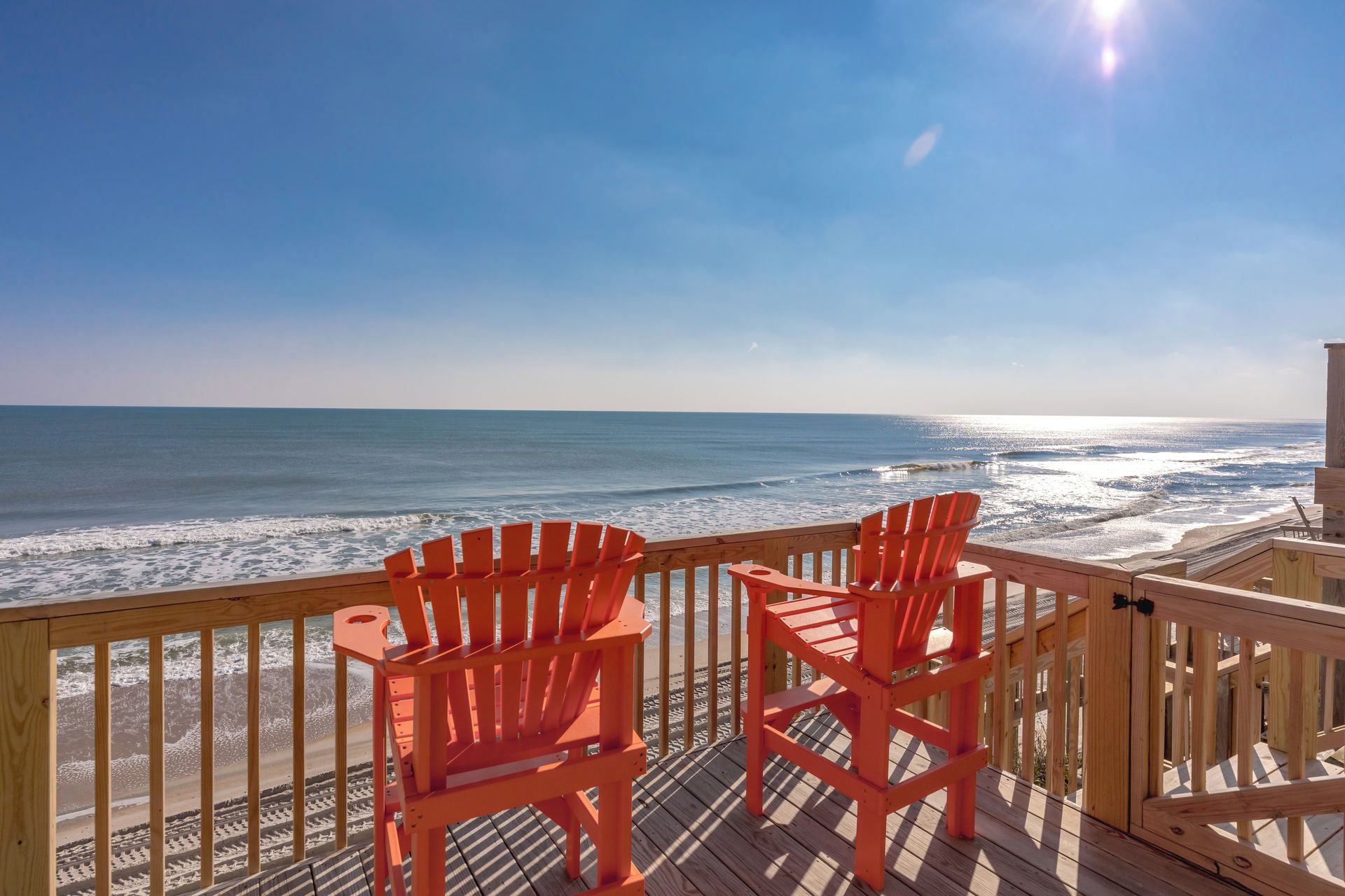 Een houten terras met twee stoelen met uitzicht op het strand.