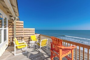 A wooden deck with outdoor seating and a view of the ocean.
