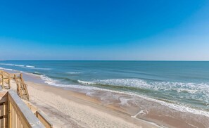 A beach with a wooden walkway leading to the water.