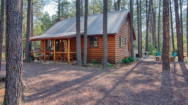 A log cabin with a porch, surrounded by tall trees. - Family Cabin in the Pines. All Wood! Charming memory-maker. (Pinetop-Lakeside)