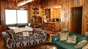 A cozy cabin interior with two sofas, a dining table, and a kitchen area. - Family Cabin in the Pines. All Wood! Charming memory-maker. (Pinetop-Lakeside)